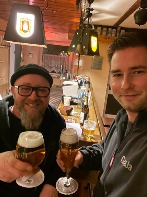 Zwei Männer stoßen mit Bier in der Kneipe an